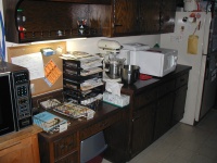 This is the "mail sorting" area.  The desk has bins for incoming mail, bins for each person in the house, and assorted pens/pencils in it.  Under the desk is the cat's litterbox.  On the counter to the right are the mixer and bread machine.  The microwave to the left is almost as old as I am.