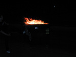 A flaming dumpster being raced down the street with kicks to the side of it to keep it from crashing into parked cars.